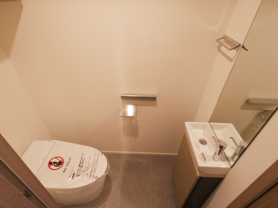鏡と小さな手洗い水栓付きのトイレ